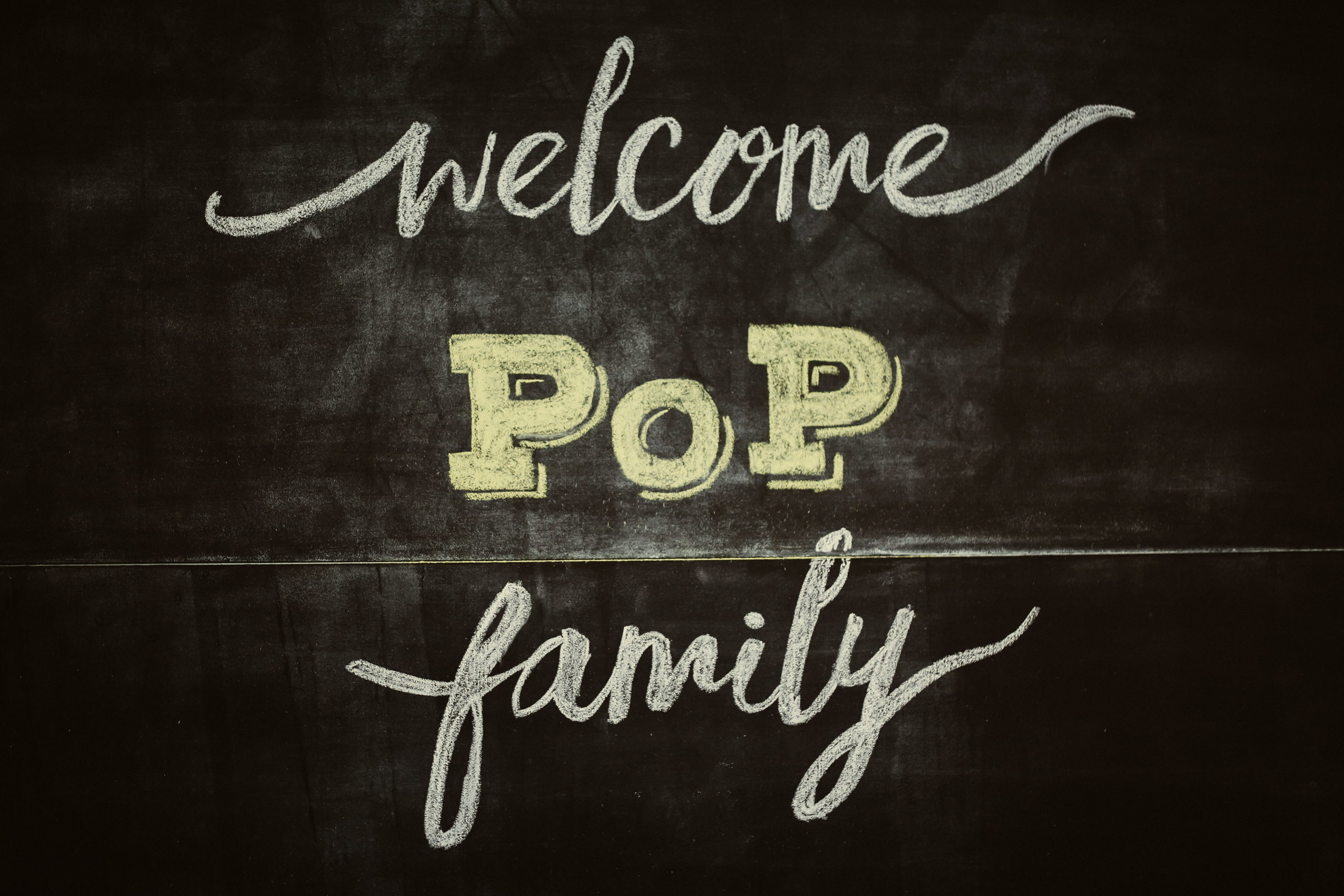 Chalk writing on a black board reads 'Welcome PoP Family'