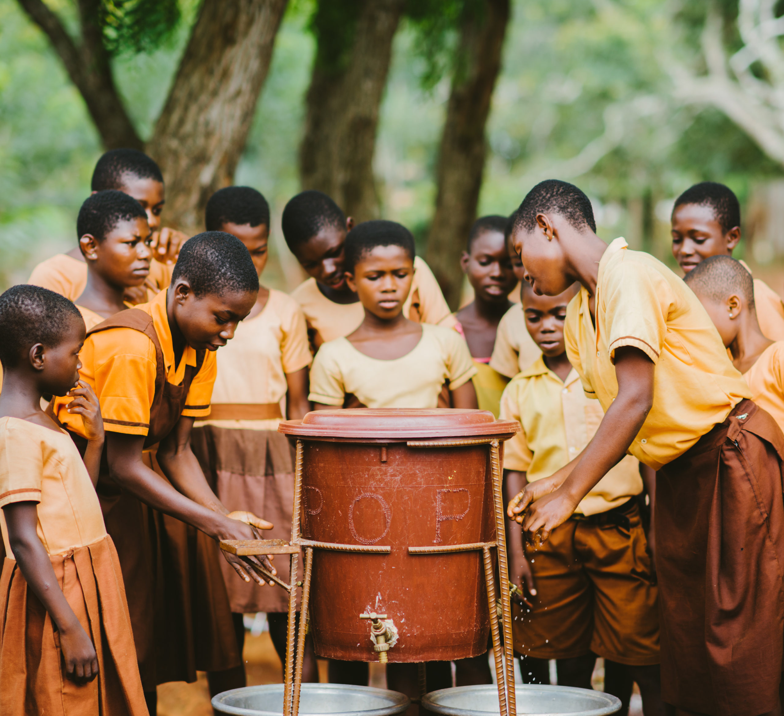 A group of students in Ghana use a handwashing station provided by PoP.