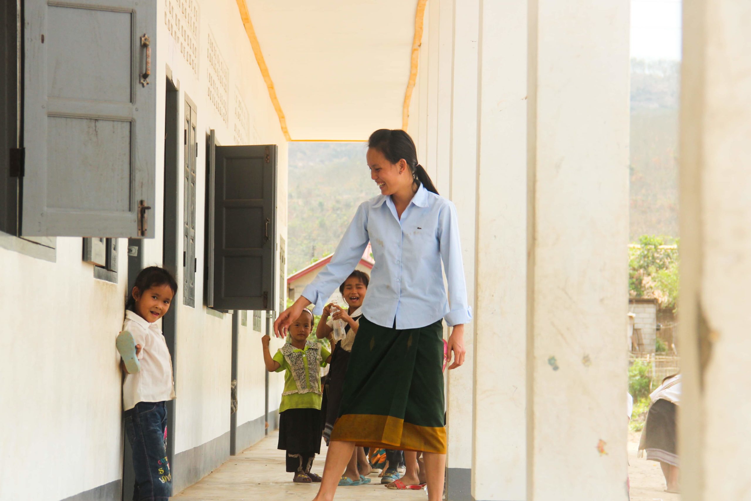 Teacher plays with students outside class in Laos.