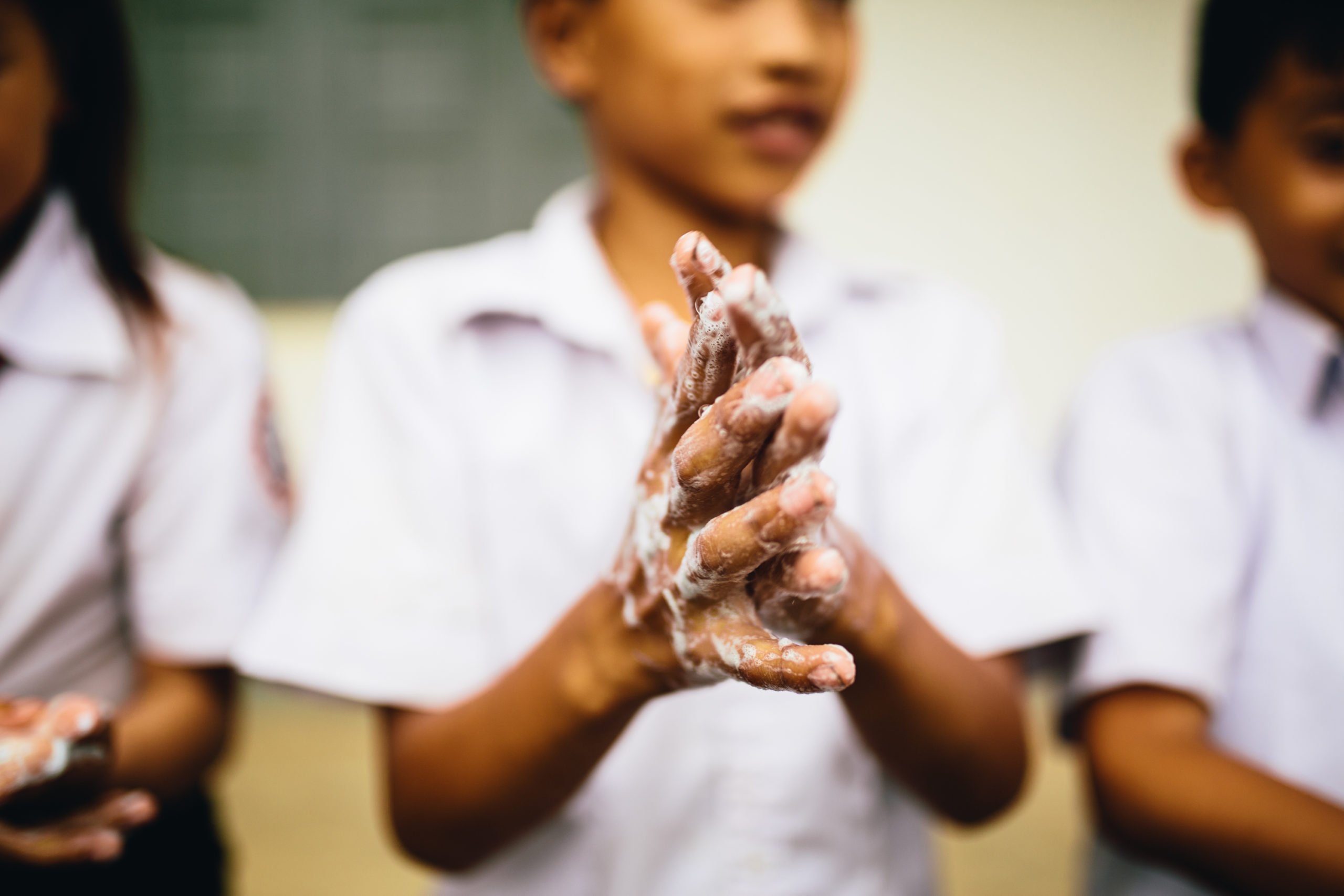 A student in Laos washes their hands with soap at a PoP-provided handwashing station.