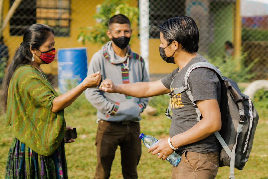 A PoP employee greets members of a community in Guatemala with a fist bump.